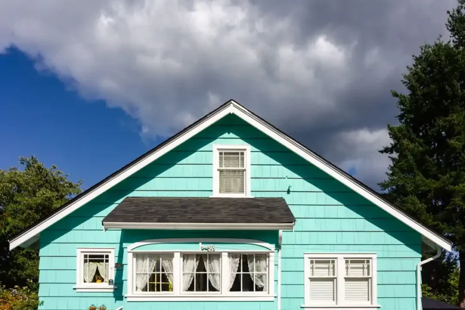 Charming blue residential house with white window trim and a black roof showcasing classic suburban architectural style.